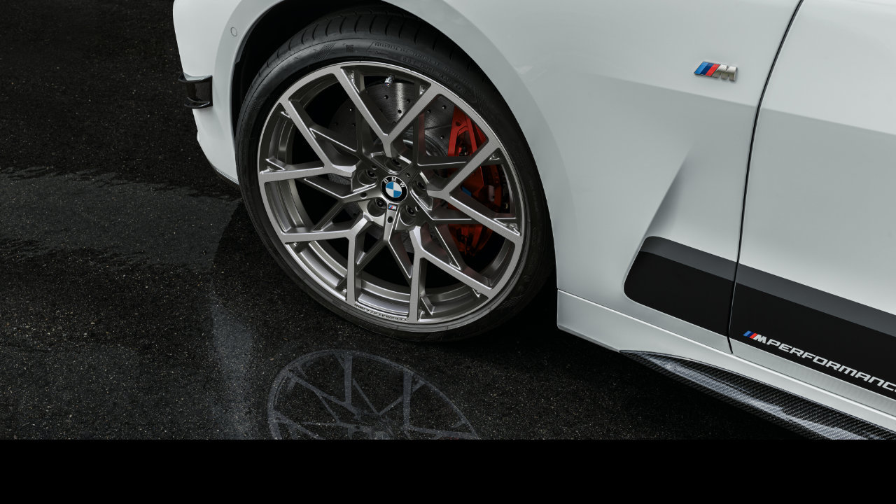 The left front wheel and tire of a white BMW M model.
